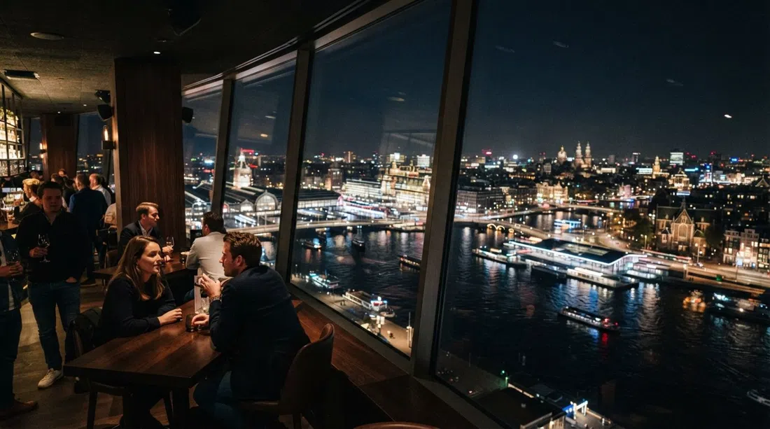 el bar Madam en la planta 20 de la Torre A'DAM de noche, con vistas panorámicas del IJ y las luces de la ciudad extendidas bajo las ventanas