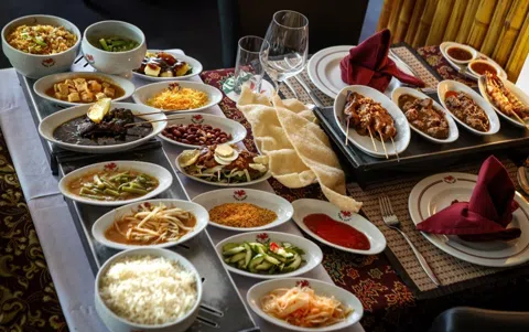 Amsterdam's Indonesian rijsttafel — the elaborate rice-table feast born in colonial Indonesia that became Amsterdam's most distinctive dining tradition. The tokos, the family-run restaurants, and the dishes that tell a complicated history.